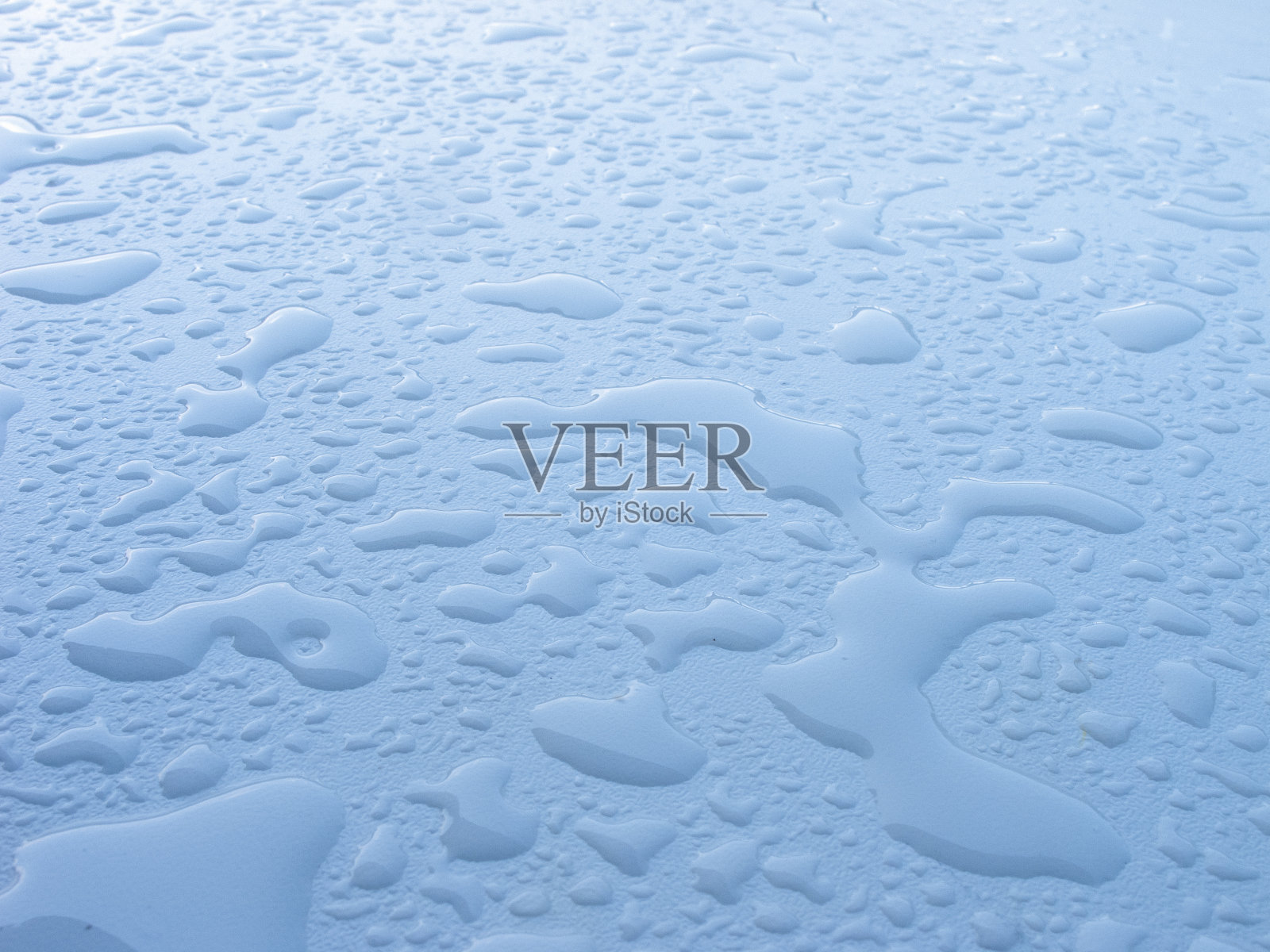 大大小小的水珠落在白色的平面上,光线柔和,雨后的背景自然照片摄影图片