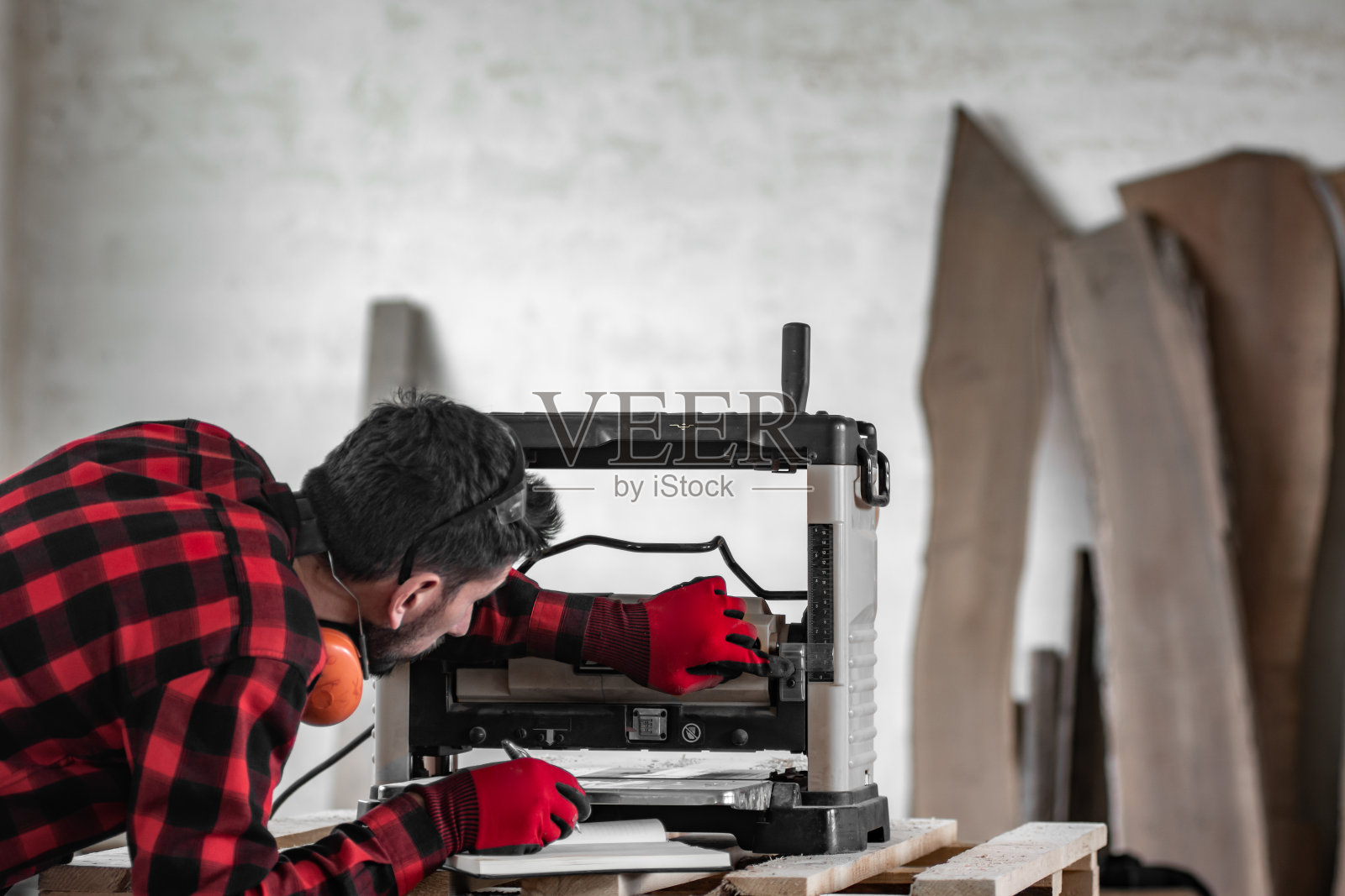一个穿着红色格子衬衫的木匠正在调整手提刨床照片摄影图片