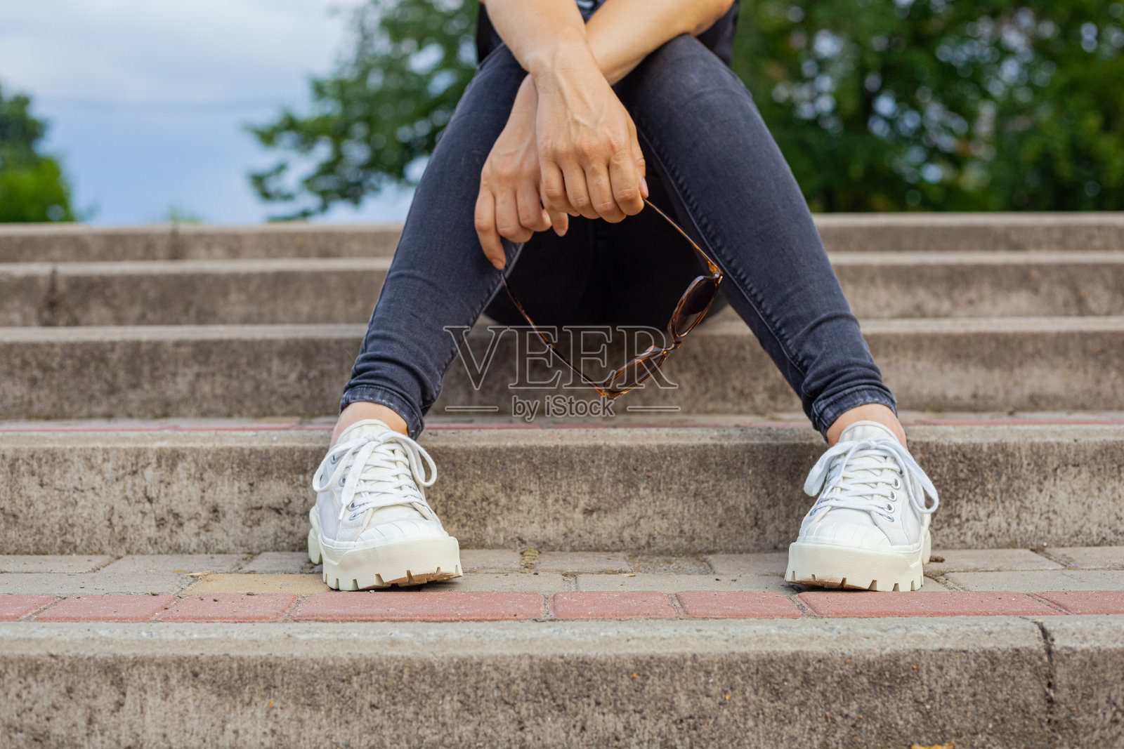 女孩坐在台阶上,手里拿着墨镜照片摄影图片