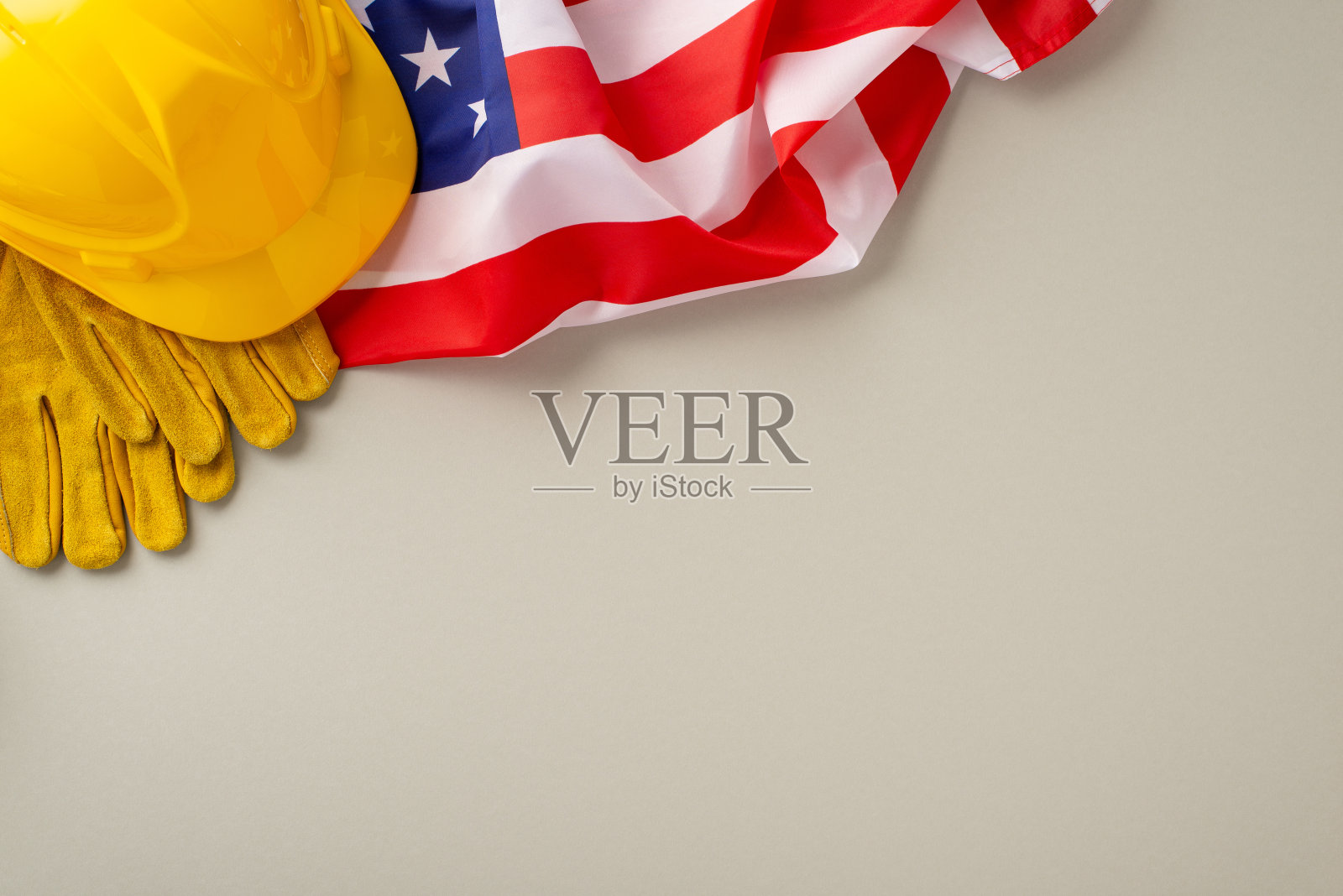 以建筑为主题的劳动节庆祝活动:用这个迷人的自上而下的快照点燃兴趣,在浅灰色的背景下,有国旗,工作头盔,手套。理想的劳动节促销或广告照片摄影图片