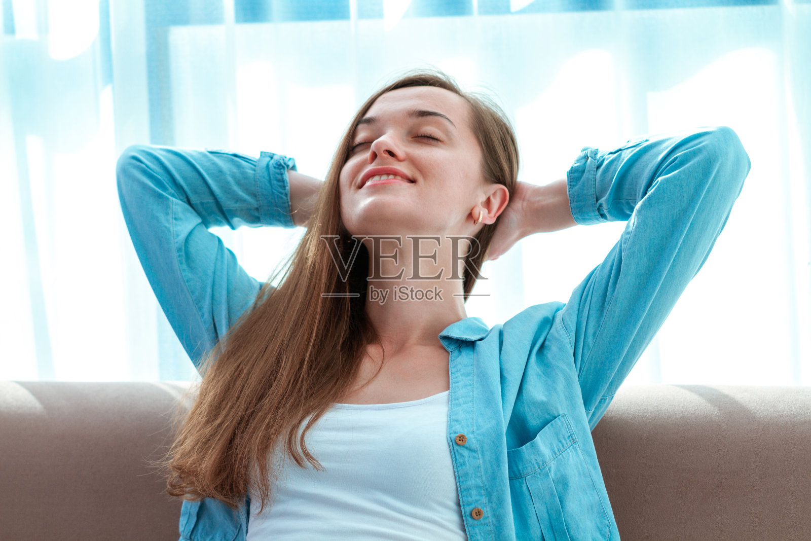 年轻,美丽,快乐,放松的女人在漫长的一天工作后,在家里的沙发上休息,享受孤独,宁静照片摄影图片