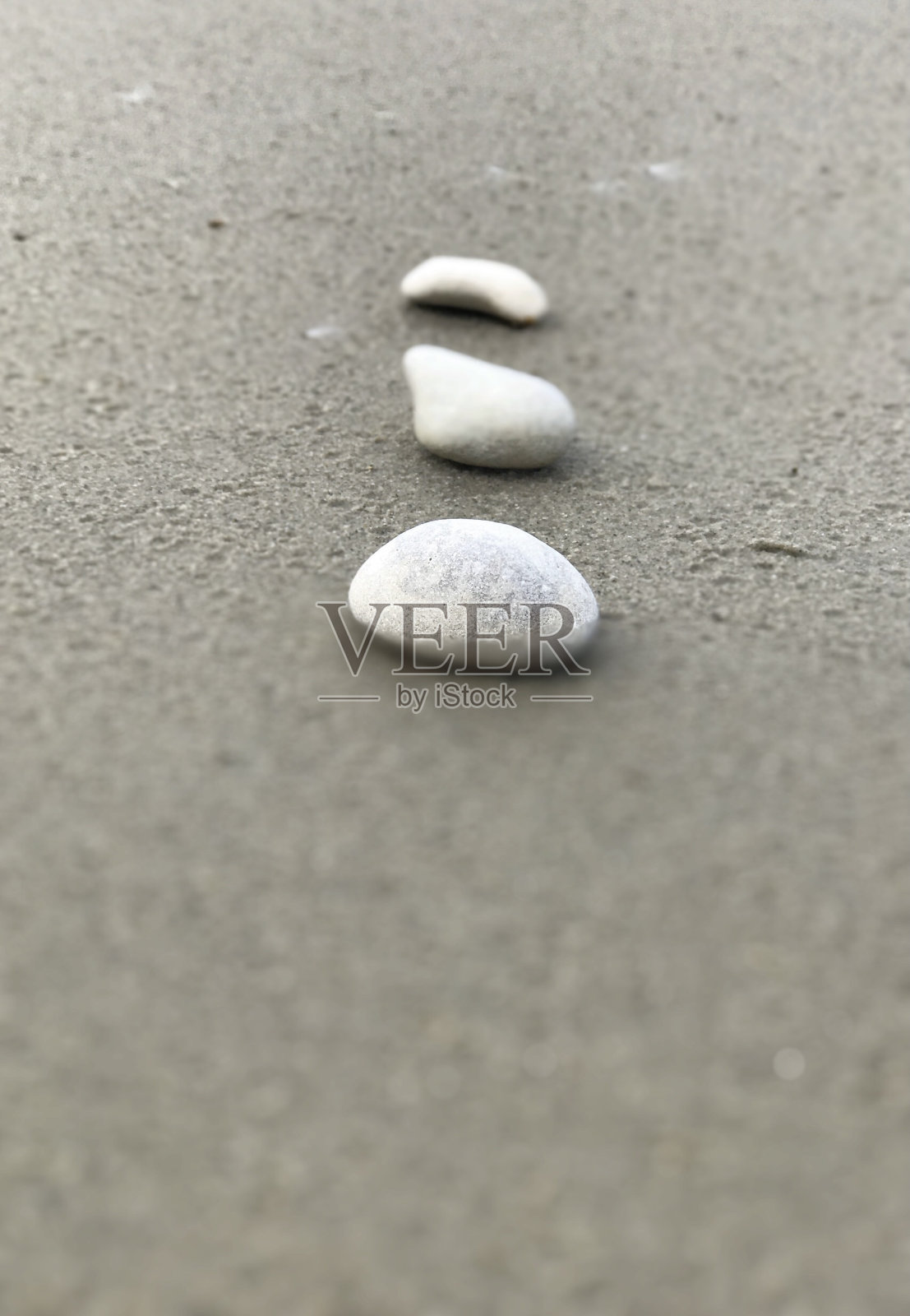 简单的近景垂直排列的三个白色的石头在灰色的沙滩照片摄影图片
