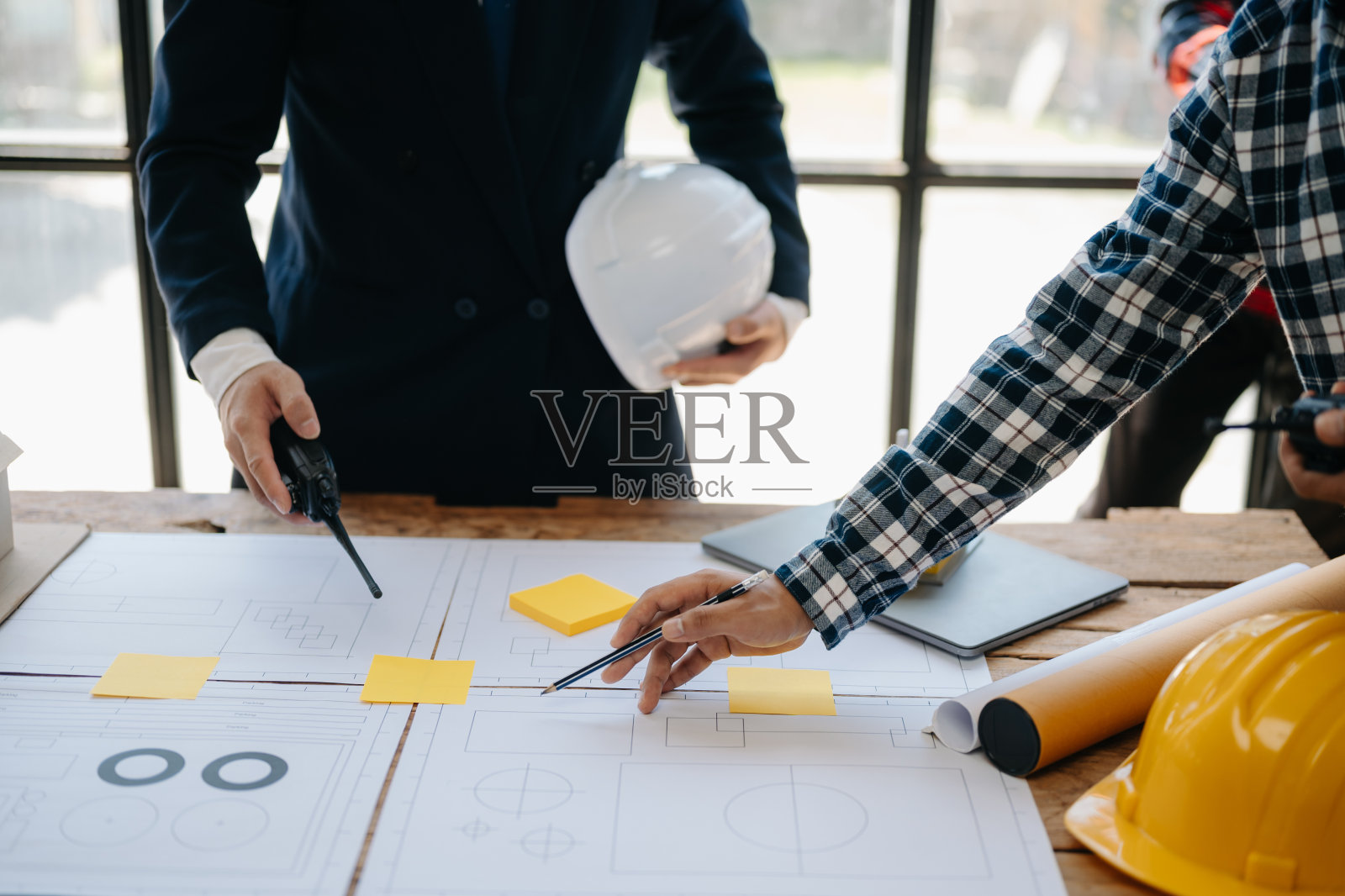 工程师办公桌上放着实物纸和模糊的平板电脑,工程师团队努力咨询他们的建筑项目。在办公室照片摄影图片