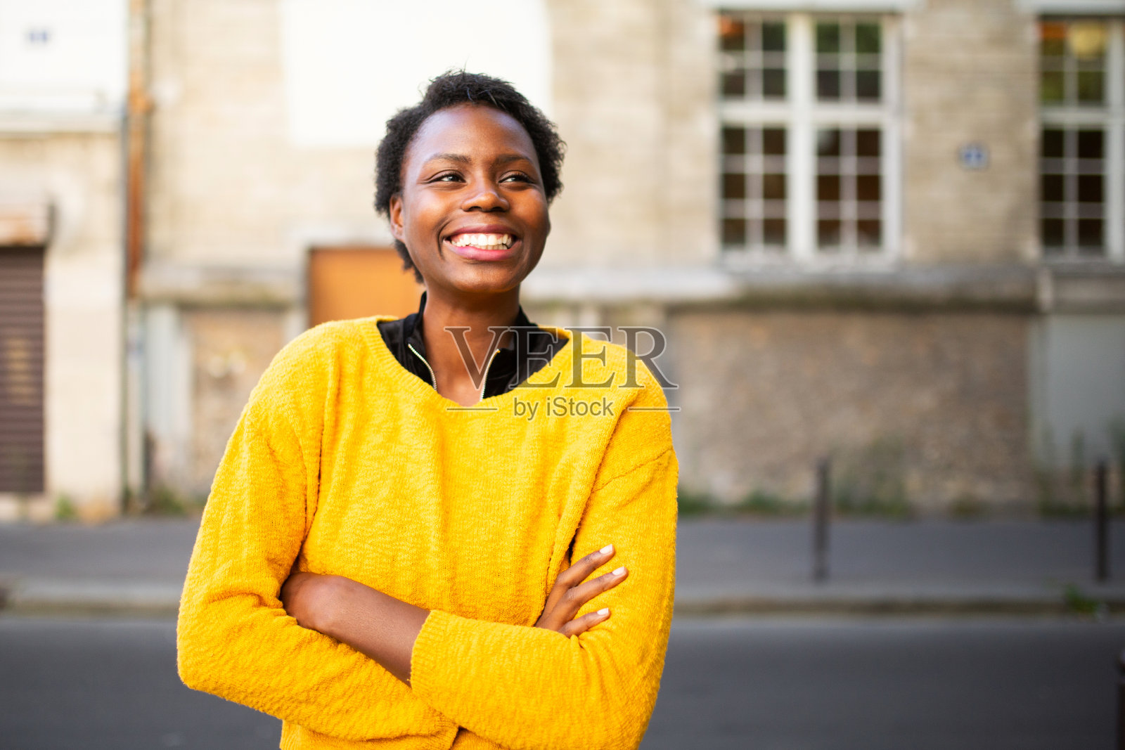 快乐的年轻非洲女人站在外面,望着别处照片摄影图片