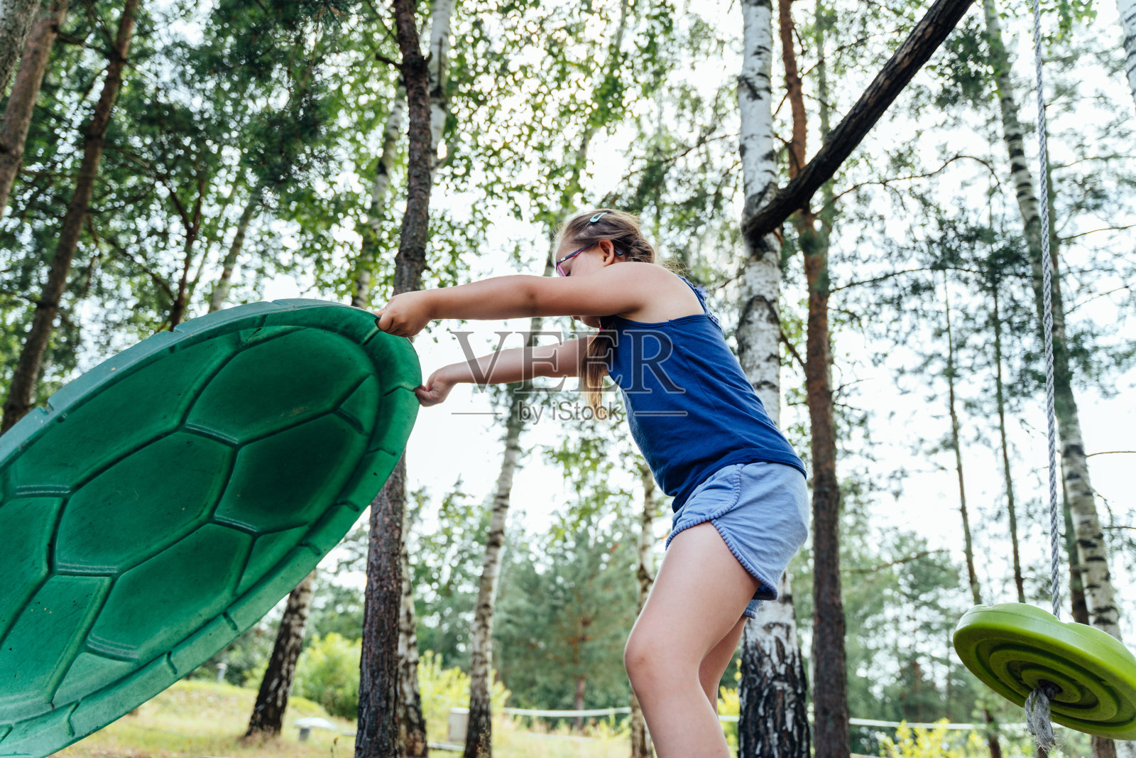 一个可爱的小女孩在操场玩沙盒玩秋千的低角度视角。特殊需要儿童的娱乐概念。照片摄影图片