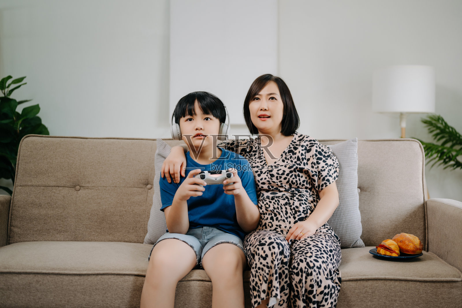 妈妈和儿子一起坐在家里房间的沙发上玩电脑游戏照片摄影图片