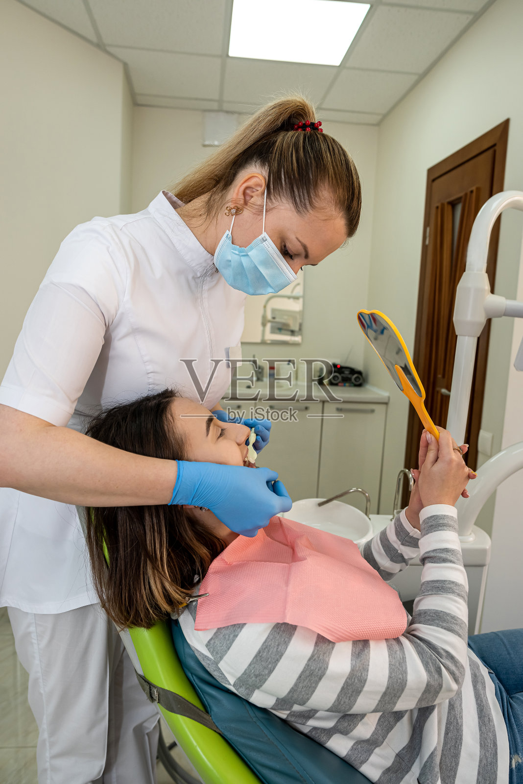 牙医拿着漂白治疗的样本给病人选择颜色照片摄影图片