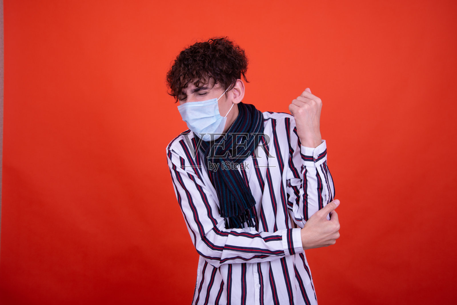 有健康问题的年轻有魅力的情绪化男孩在橘黄色背景的工作室里摆姿势。照片摄影图片