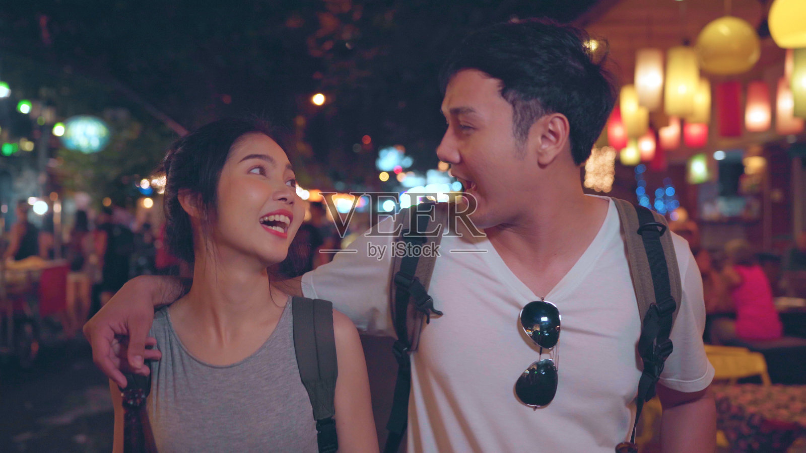 亚洲背包客夫妇在泰国曼谷旅行,甜蜜的夫妇在考山路闲逛时喝着酒或啤酒。情侣游泰国的概念。照片摄影图片