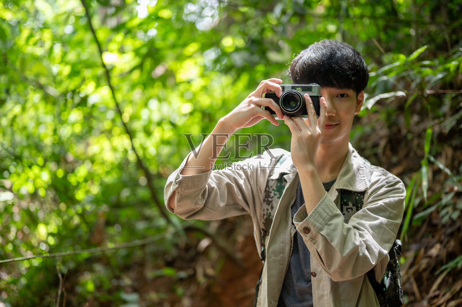一位快乐的年轻亚洲男性徒步旅行者在徒步旅行时用他的老式胶片相机拍照照片摄影图片