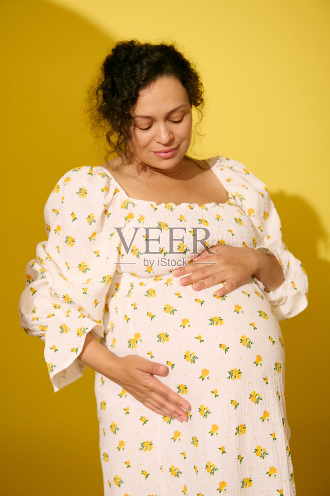 怀孕的美女穿着背心裙,轻轻地抚摸着她的肚子,体验着她无忧无虑的快乐怀孕的快乐时刻照片摄影图片