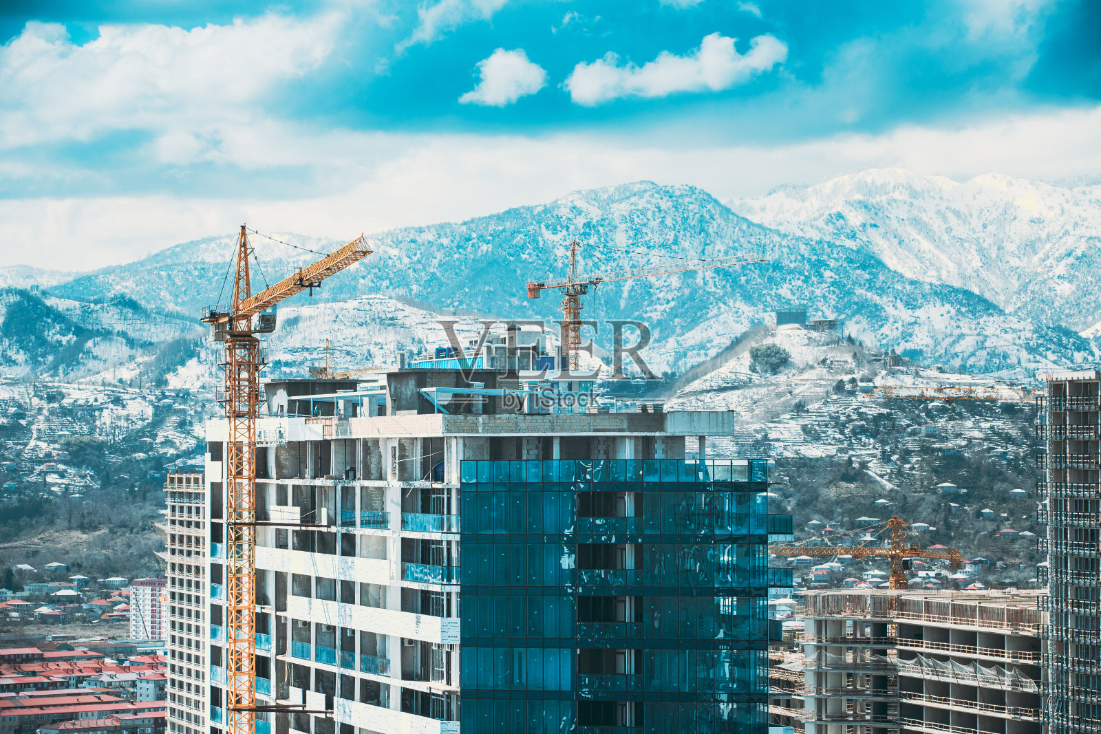 某新建多层住宅楼的开发使用了施工起重机。蓝天上的新住宅多层住宅。房地产、开发行业。高层住宅高架景观城市天际线。光照明照片摄影图片