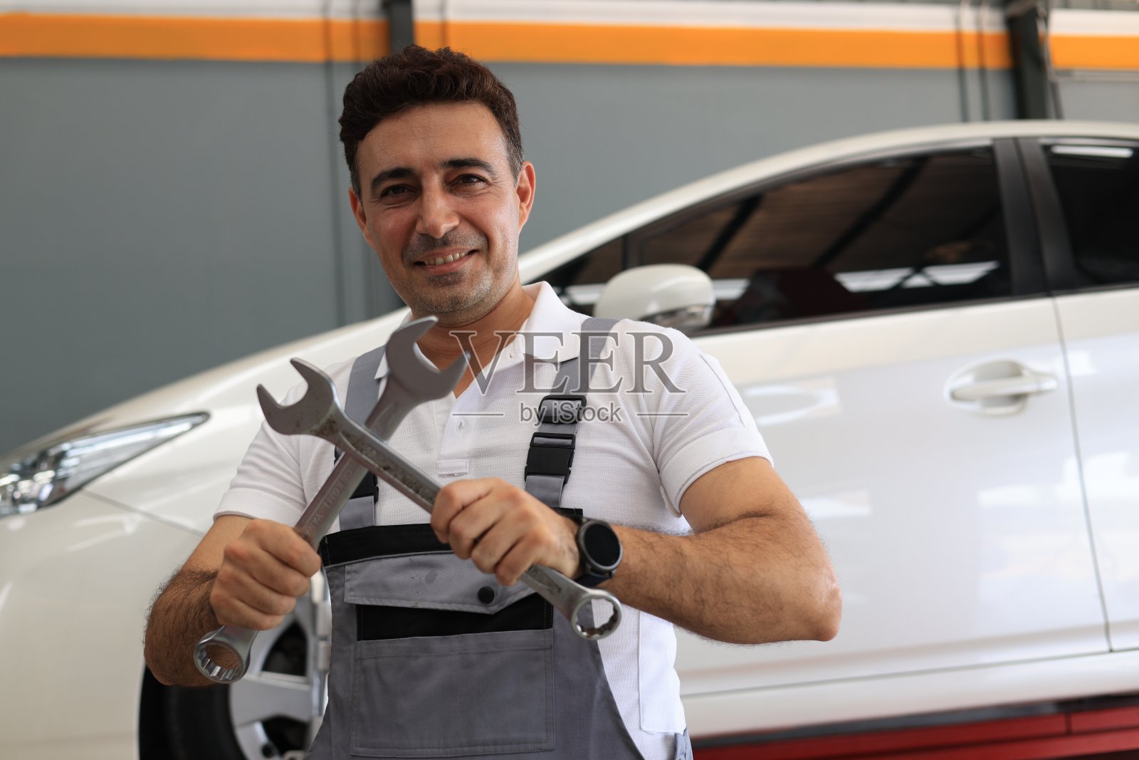 机械工程师站在他的肩膀上扳手在他的工作在汽车服务。照片摄影图片