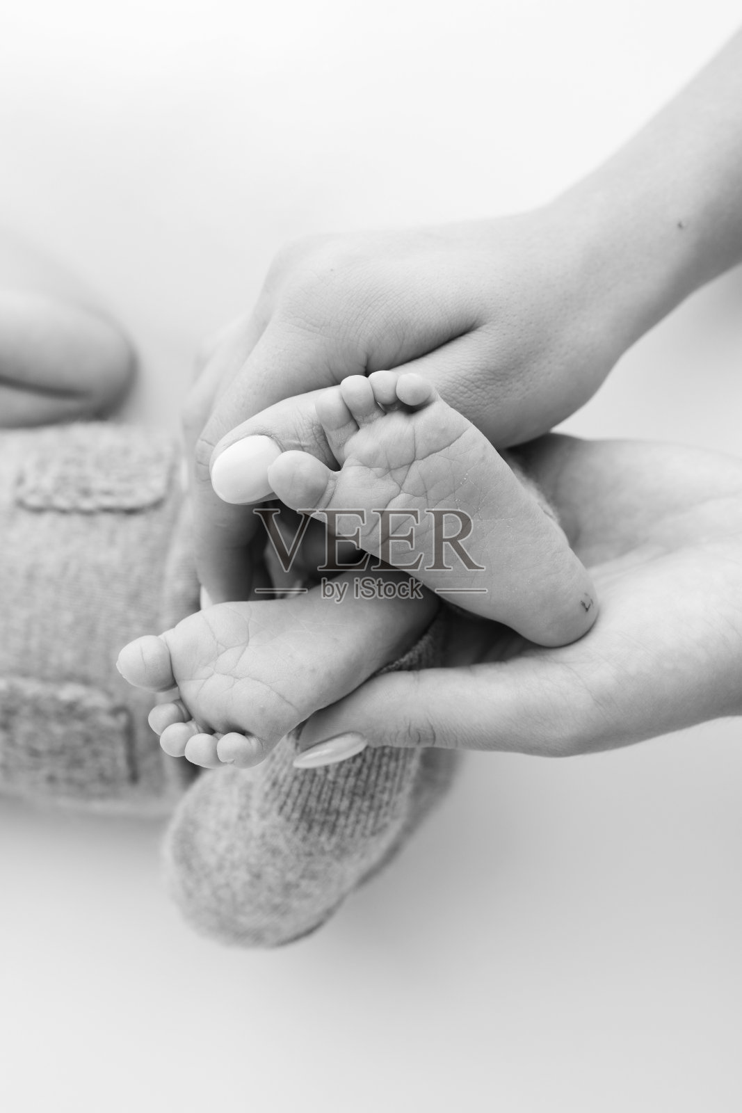 父亲的手掌,母亲的脚都抱着刚出生的婴儿在白色的背景。新生儿的脚放在父母的手掌上。孩子的脚趾、脚后跟和脚的照片。照片摄影图片