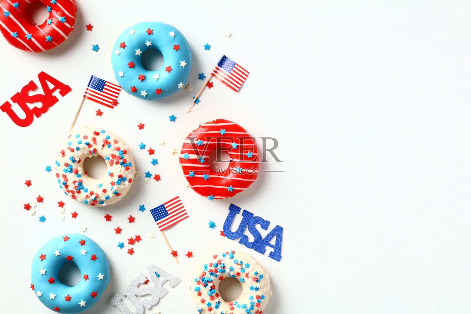 平铺的美国甜甜圈,美国国旗,白色背景上的五彩纸屑。7月4日派对邀请卡设计。照片摄影图片