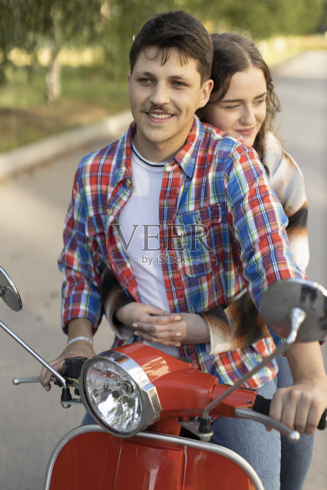 一对年轻夫妇骑着小摩托穿过城市的街道照片摄影图片