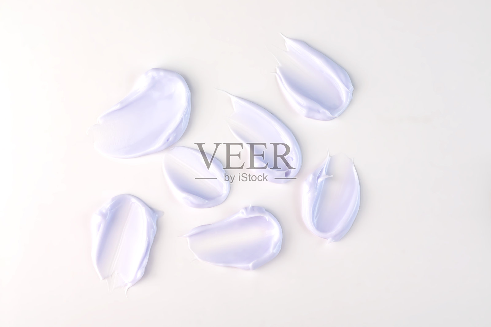 化妆品涂抹紫色保湿乳液隔离于白色,挤出和涂抹部分护肤霜产品的测试。照片摄影图片