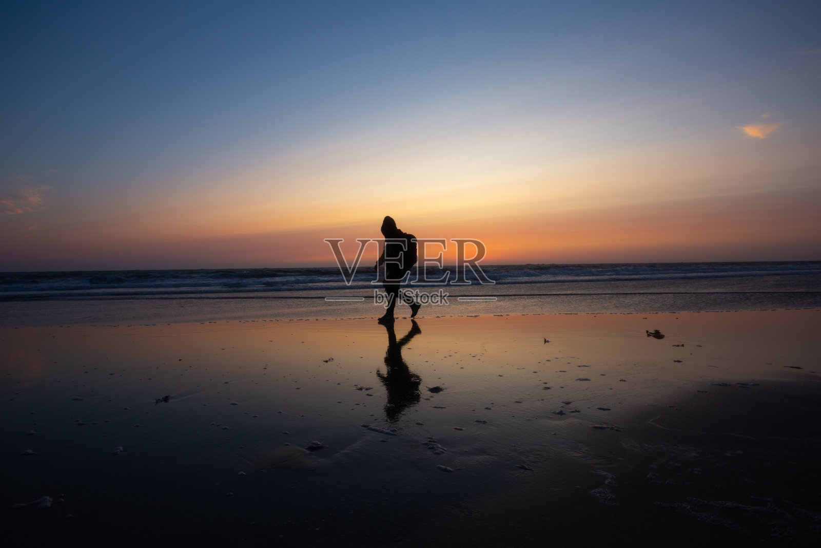 在葡萄牙布拉加的欧菲尔海滩,日落时分,朝圣者的剪影走向“圣地亚哥德孔波斯特拉”。照片摄影图片