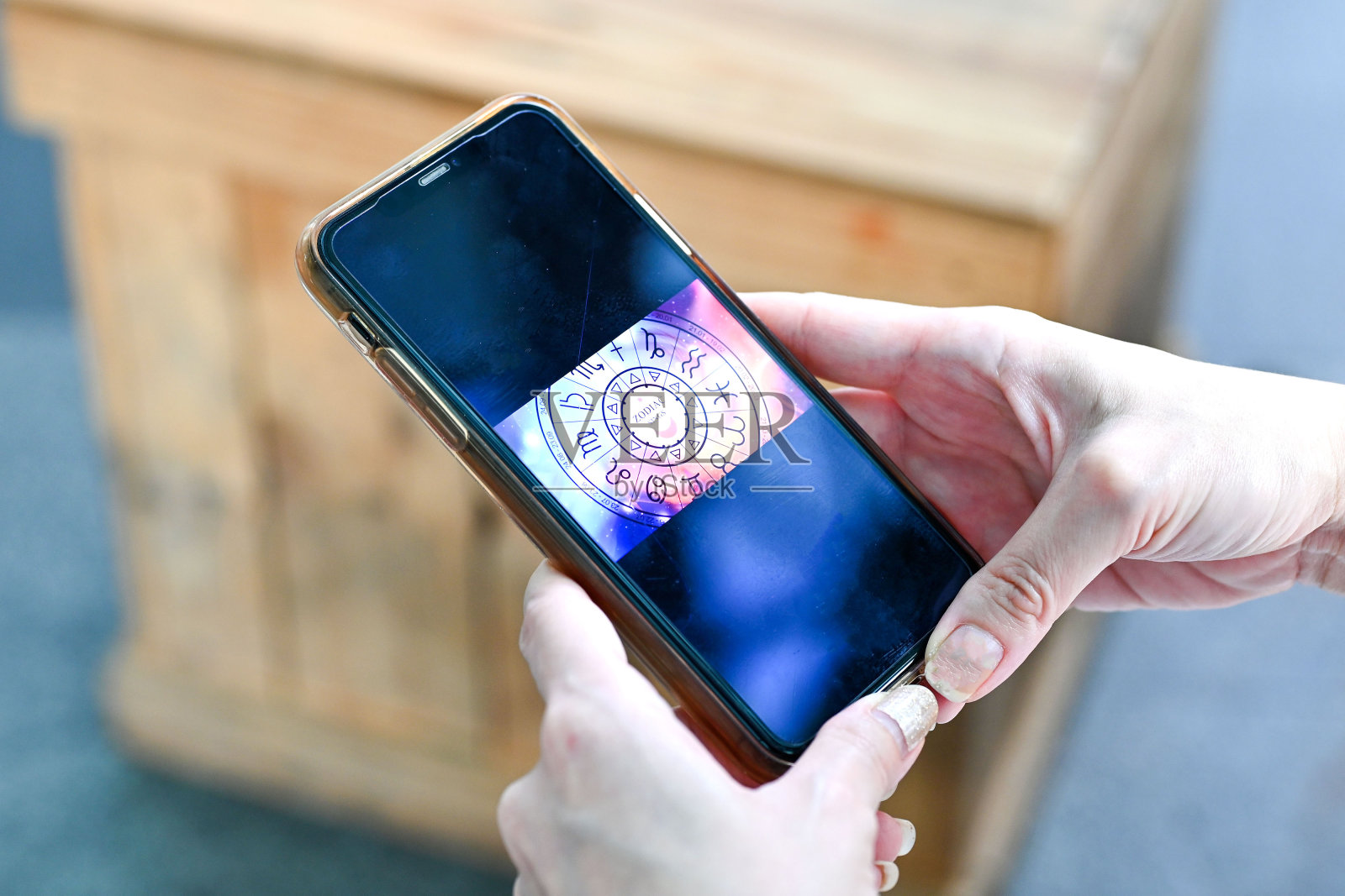 手持智能手机检查占星生肖星座移动应用程序。精神新时代,命运之轮,命运业力和宿命照片摄影图片