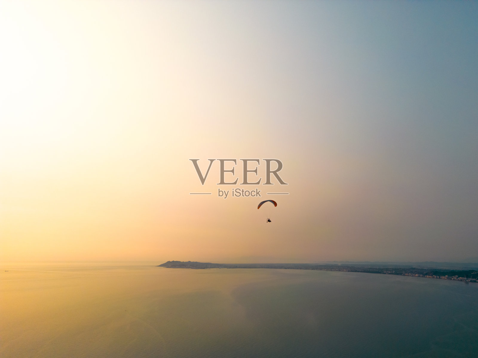 Para-motor在日落时在海洋上空飞行照片摄影图片