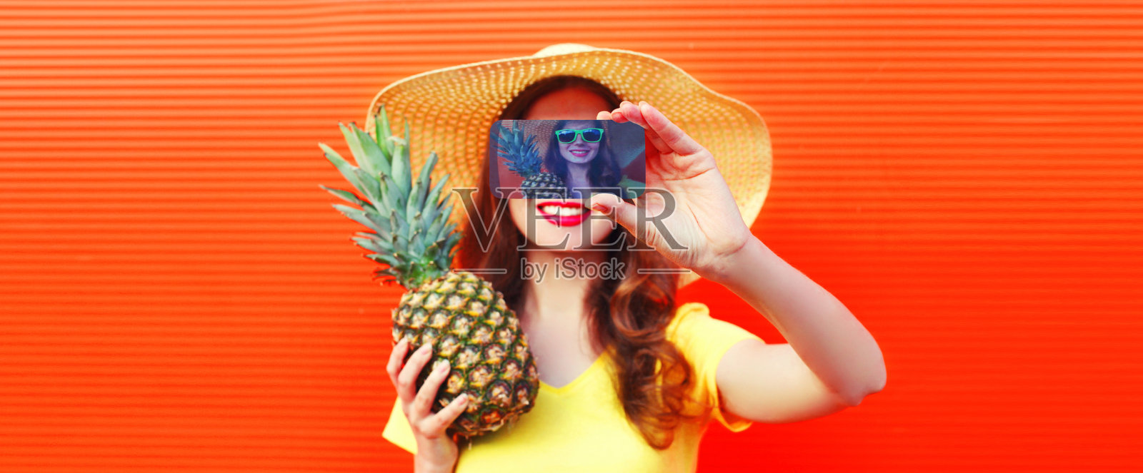 夏天肖像特写快乐微笑的女人与菠萝采取自拍智能手机戴草帽,太阳眼镜在生动的背景照片摄影图片