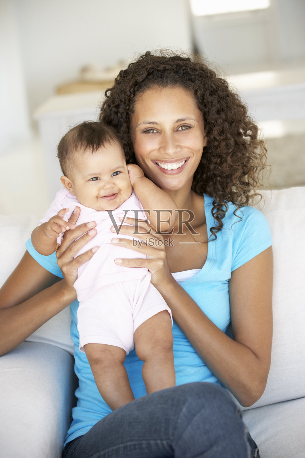 年轻的母亲和宝贝女儿坐在沙发上照片摄影图片