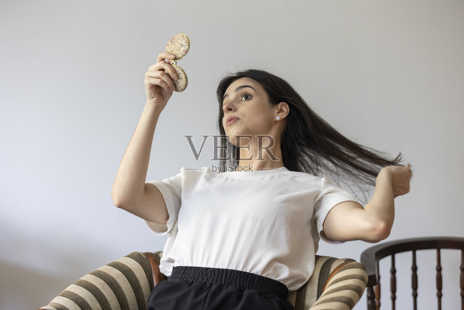 坐在扶手椅上整理头发的白人女人照片摄影图片