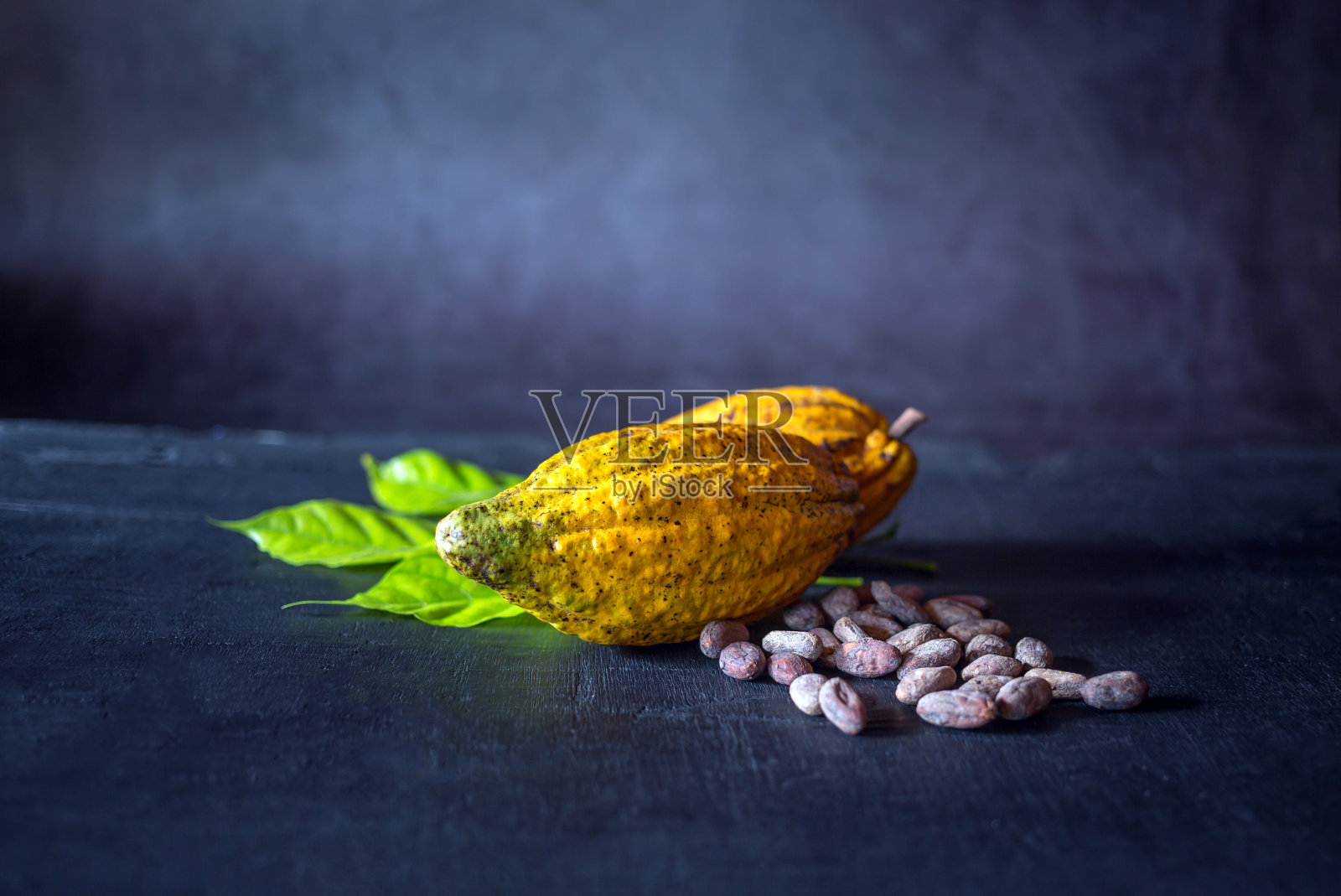成熟的可可荚和黄色的可可果实与棕色的可可豆在黑色的木制背景照片摄影图片