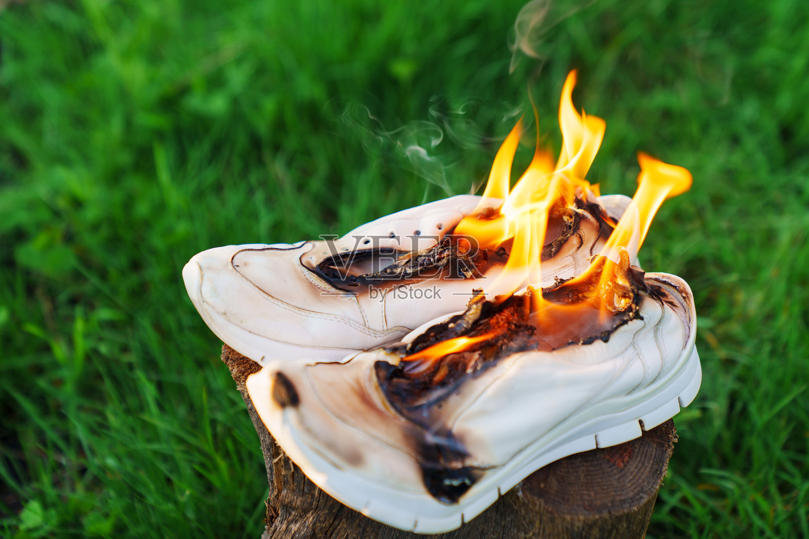 燃烧的皮革运动鞋。在树桩上的运动鞋或运动鞋着火了。照片摄影图片