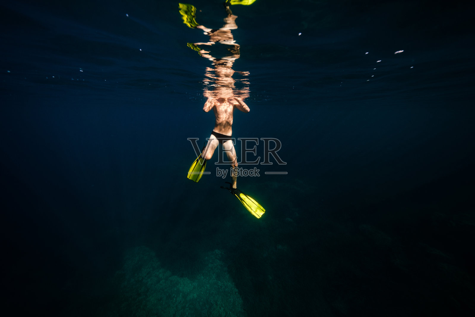 在阳光下在海底游泳的无名健美男子照片摄影图片