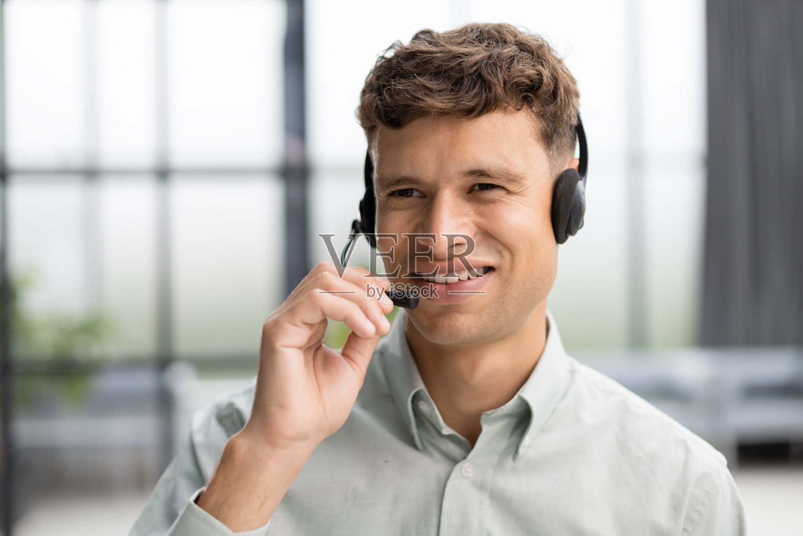 微笑友好英俊的年轻男性呼叫中心接线员。照片摄影图片