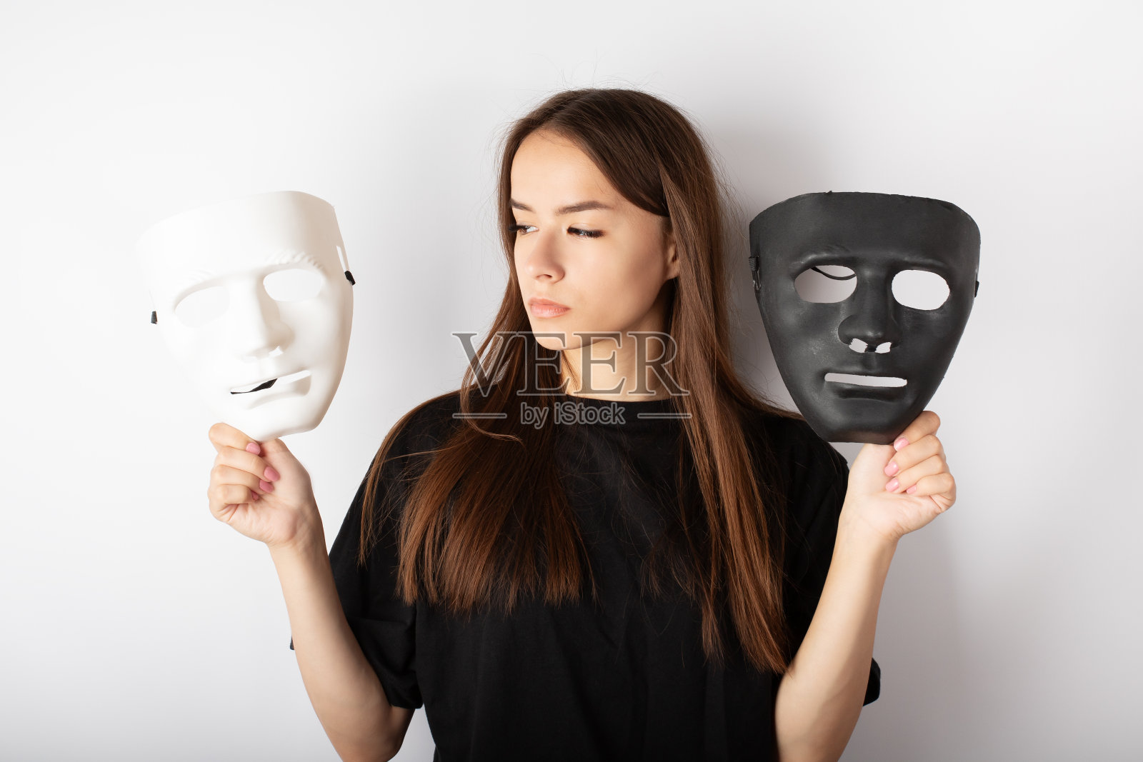 情绪波动,从快乐到抑郁,心理健康问题,一个青少年带着黑白面具,一个年轻女演员选择一个角色进行表演照片摄影图片