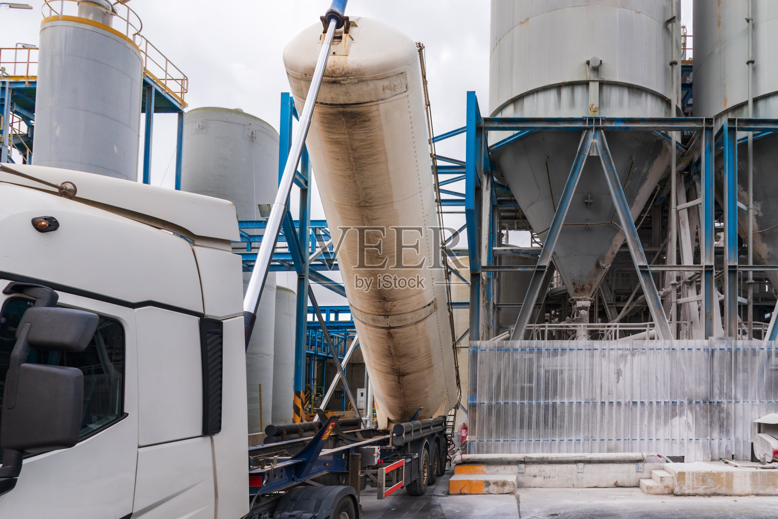 有倾卸槽的卡车,用于运输粉状物质的筒仓,在工厂卸货,槽抬高。照片摄影图片