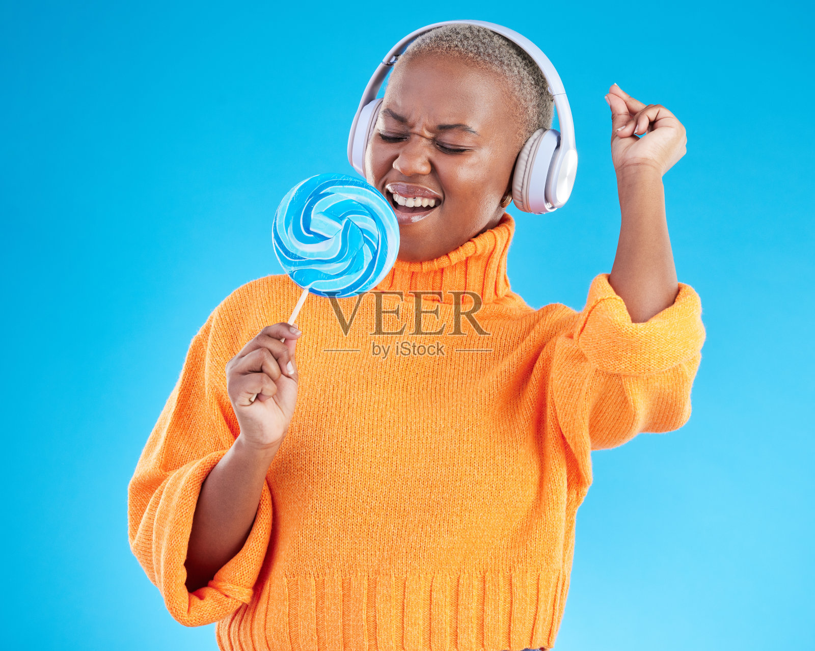 音乐耳机,棒棒糖或黑人妇女听广播播放列表在蓝色背景下放松。糖果,糖果或女孩歌手跳舞,唱歌或播放歌曲音频或音轨照片摄影图片