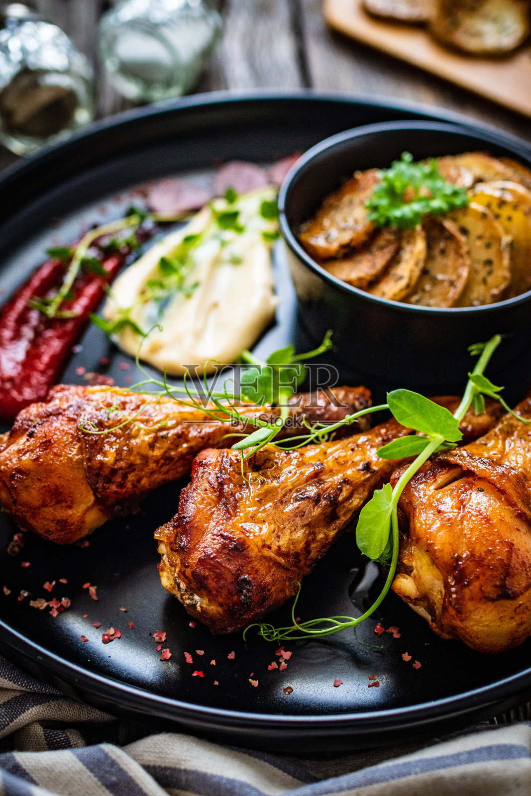 木桌上的烤鸡腿和烤土豆照片摄影图片