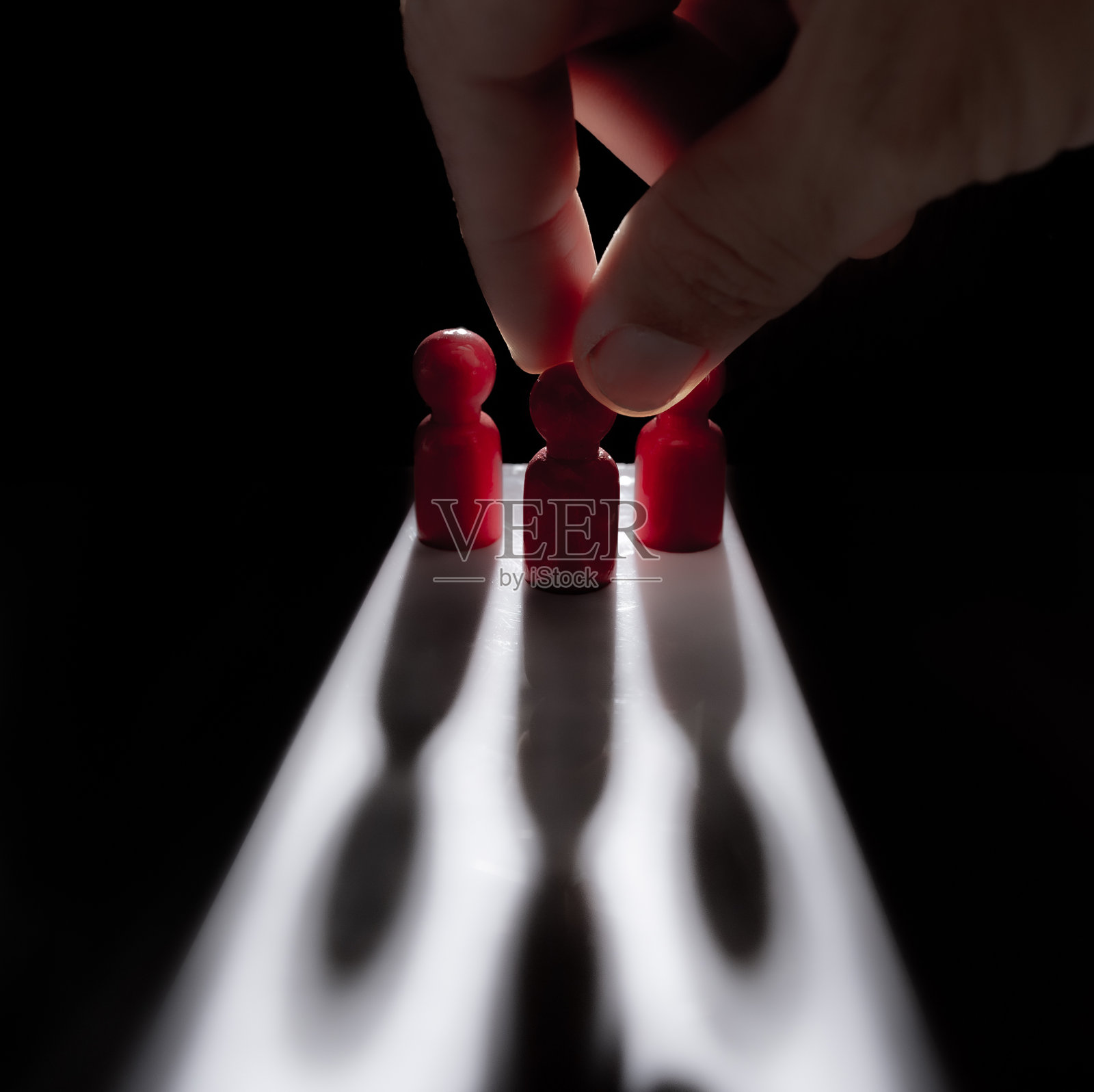 手男在黑暗背景的阴影中选择最成功的木人模型,领导概念。照片摄影图片