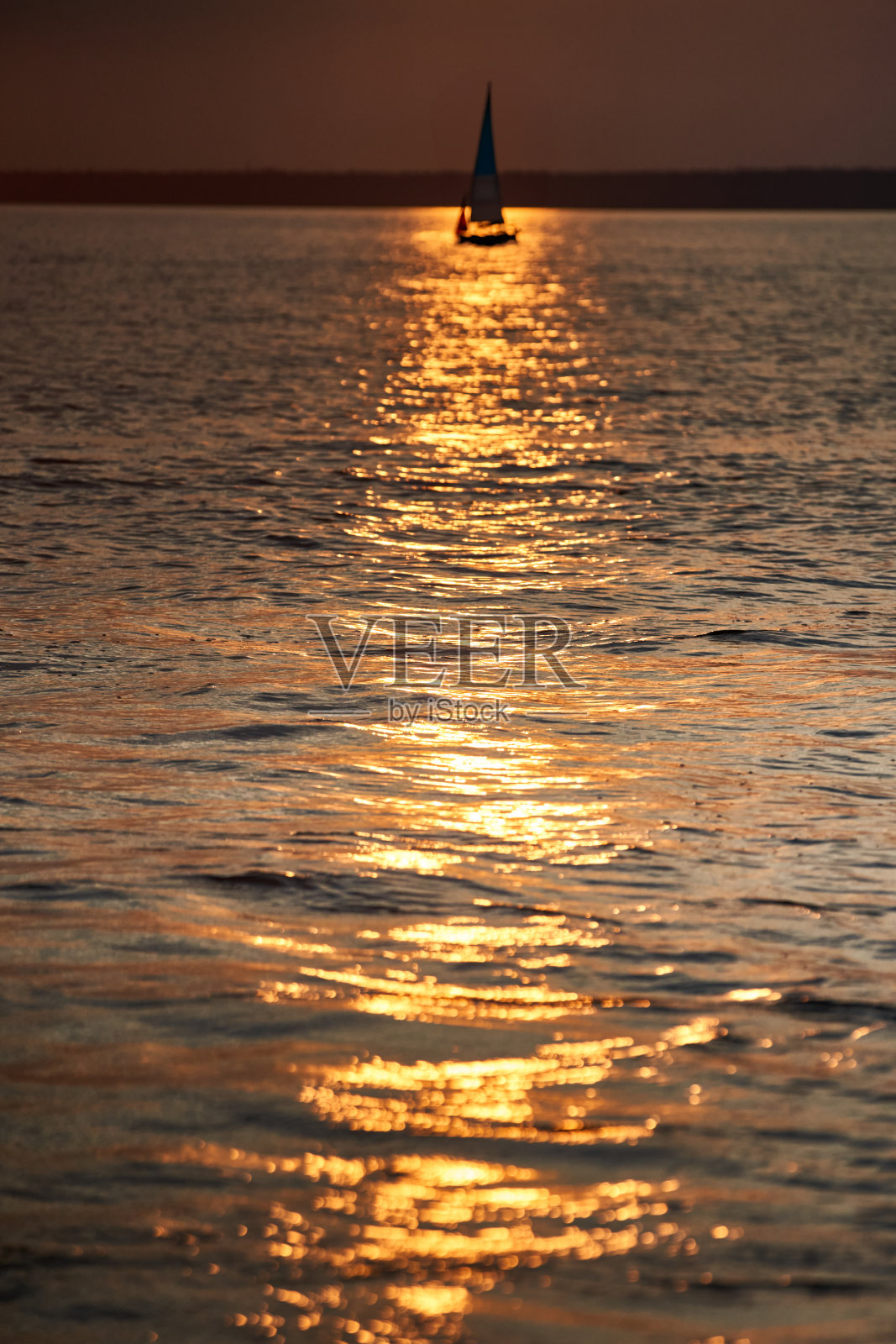 日落时帆船的景色是倾斜的,太阳在水面上的反射照片摄影图片