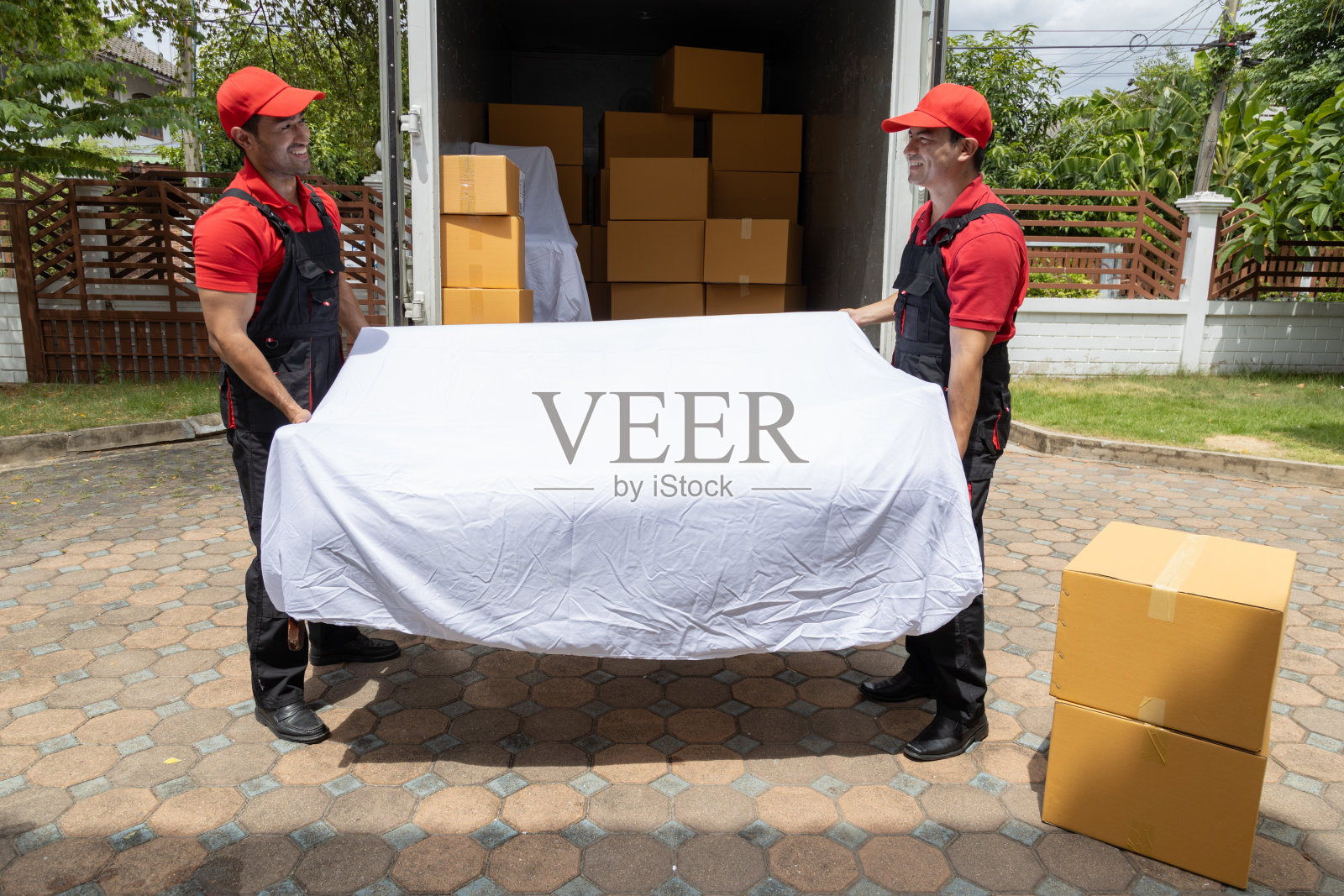 两名搬运工从一辆皮卡车上卸下箱子和家具。照片摄影图片