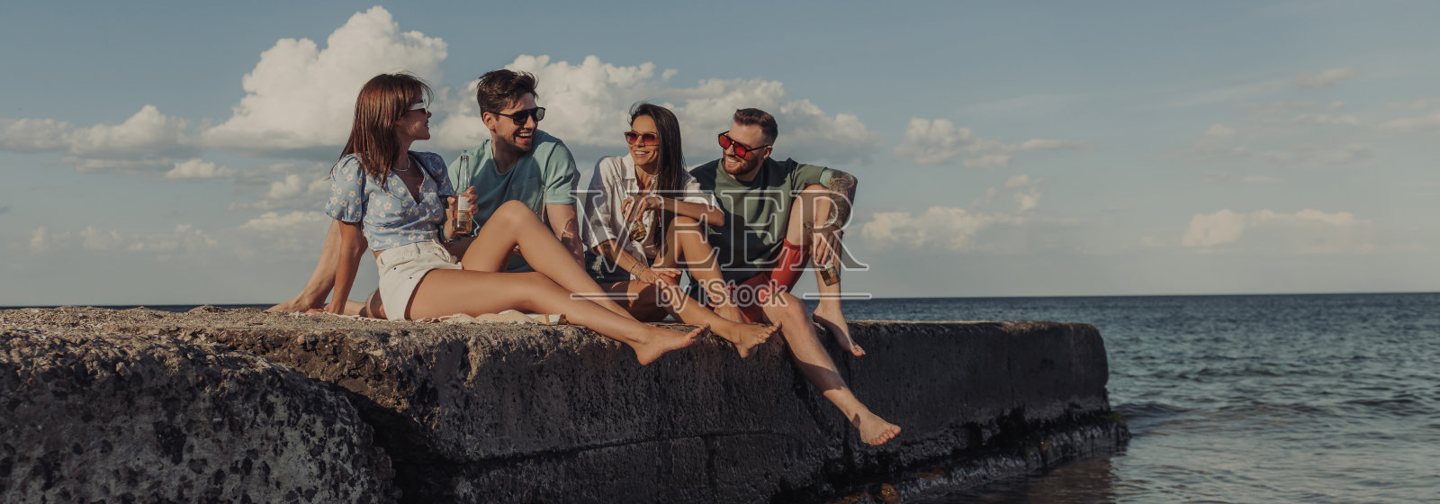 一群快乐的年轻朋友一起享受着啤酒,在海边度过无忧无虑的时光照片摄影图片