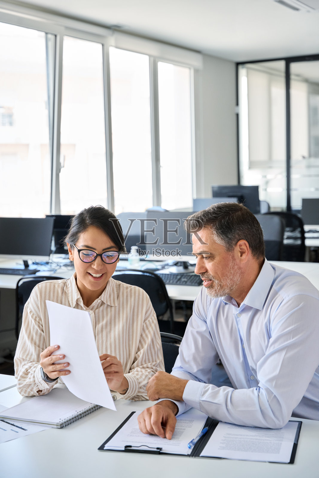 年轻的亚洲客户经理向提供法律服务的合伙人出示文件。照片摄影图片