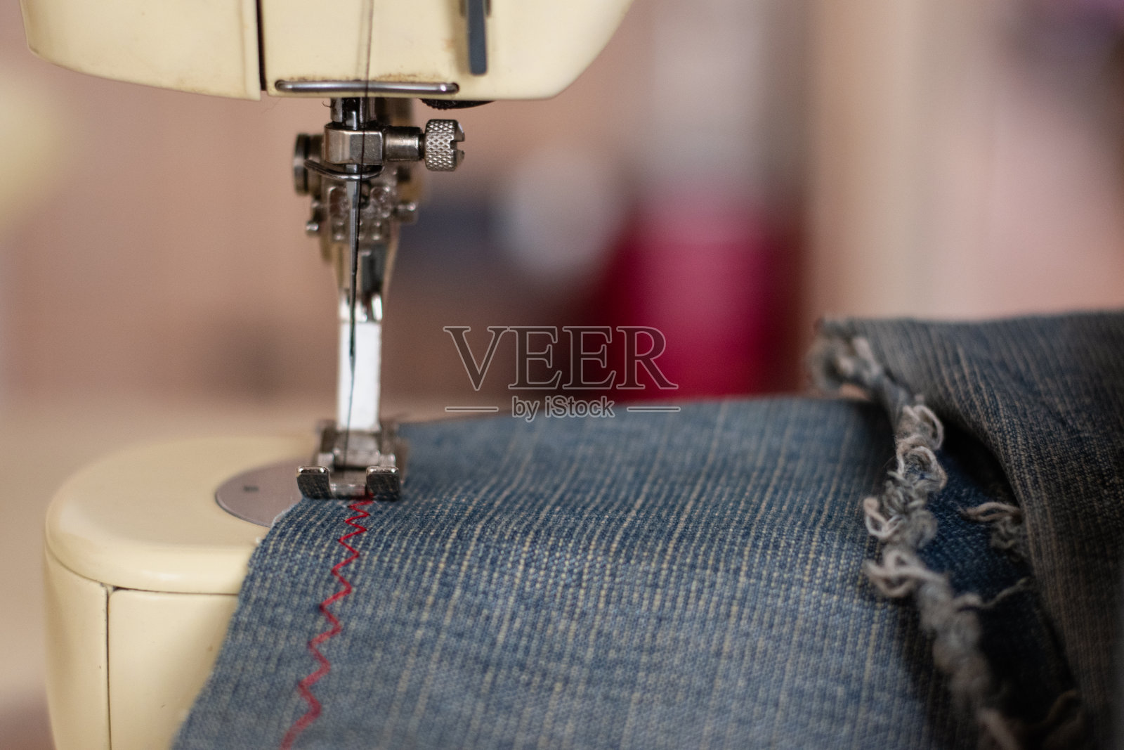 缝纫机近距离缝制牛仔裤。照片摄影图片