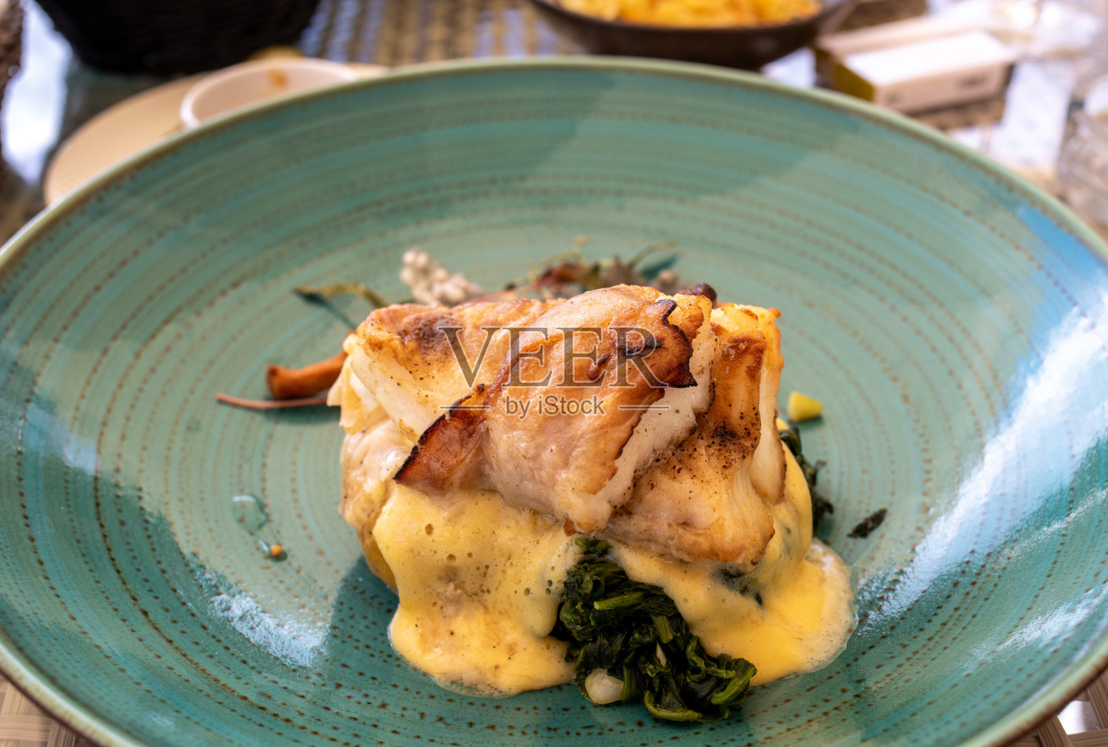 绿色陶瓷盘子里的菠菜和香草烤鳕鱼照片摄影图片