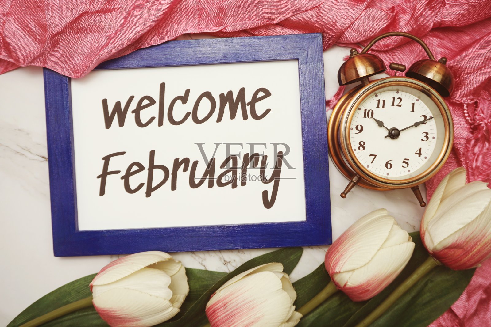 欢迎二月写在蓝色框架与郁金香花平躺在大理石背景照片摄影图片