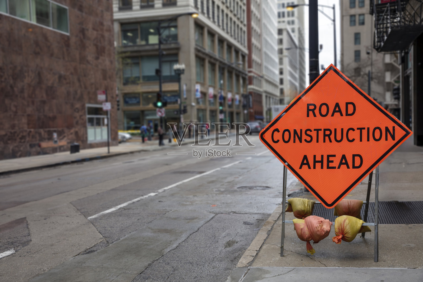 前方道路施工文字,橙色菱形标志道路警示,美国。模糊城市背景。照片摄影图片