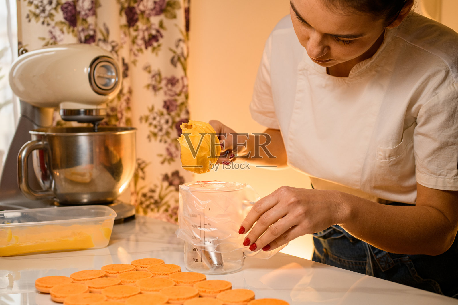 女糕点师在糖果袋里装满了新鲜制作的奶油,特写。模糊的背景照片摄影图片