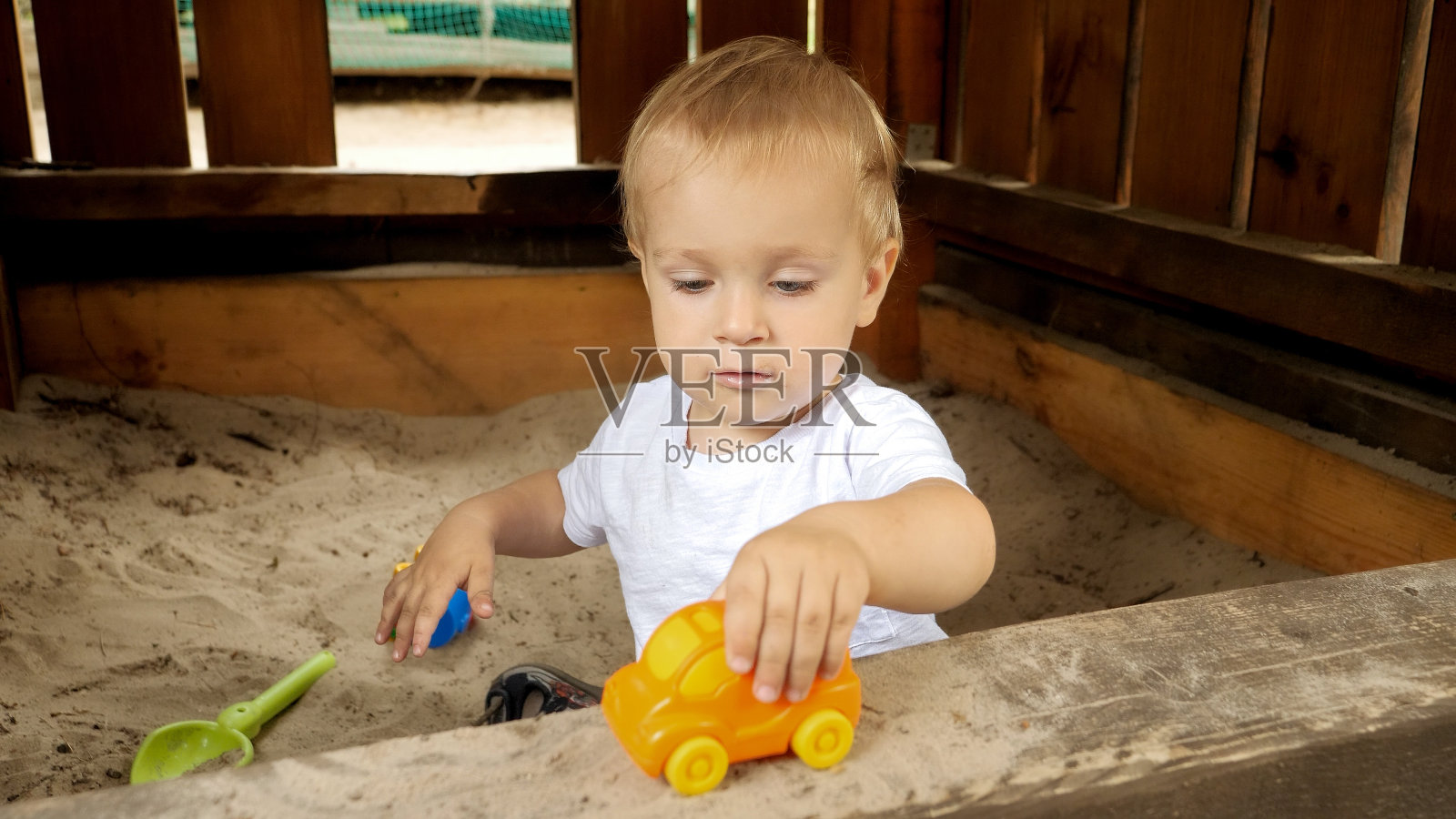 小男孩在公园的沙坑里玩五颜六色的玩具和汽车。孩子们在户外玩耍,孩子们玩得开心,暑假和假期。照片摄影图片