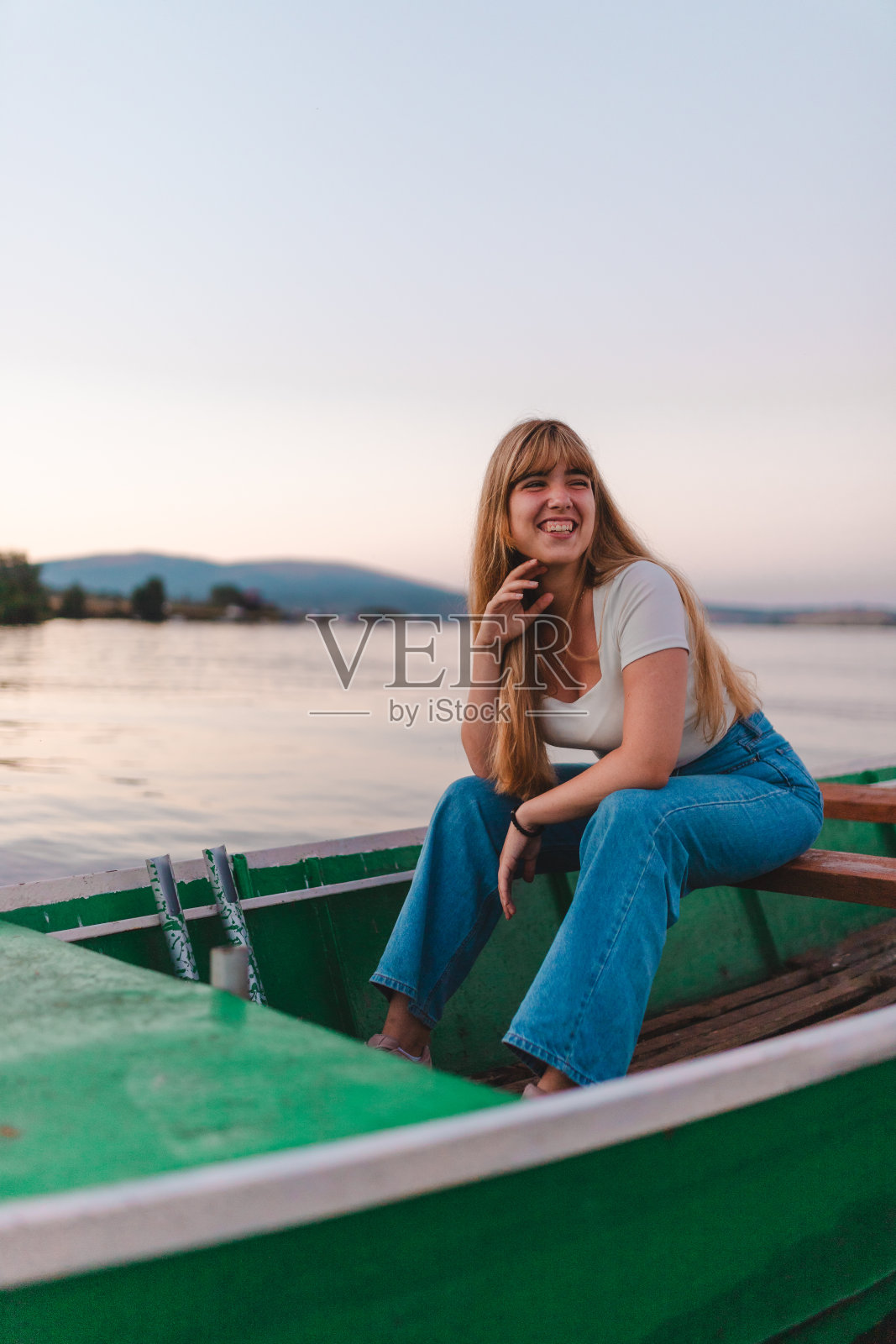 一个美丽的年轻女子坐在湖上的船上的垂直肖像照片摄影图片