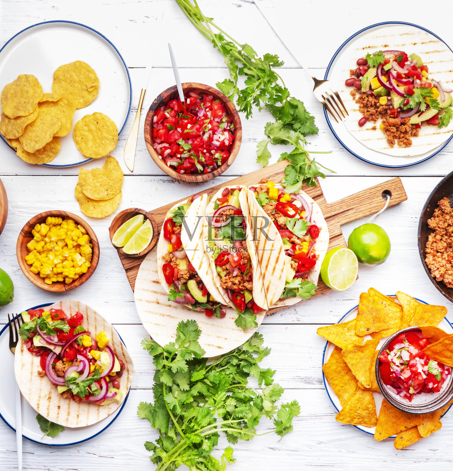 墨西哥煎玉米卷。餐桌与玉米饼,玉米片,酱汁,开胃菜和盘子。自制墨西哥菜烹饪场景。白色桌面背景,顶视图照片摄影图片