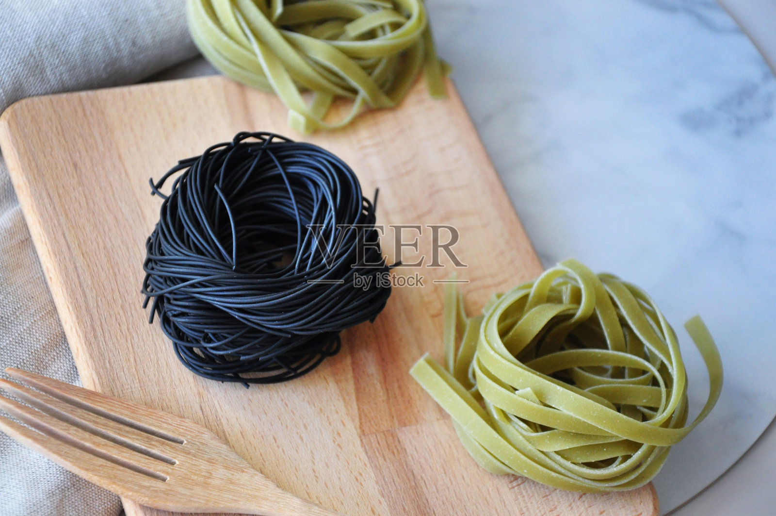 生黑色和绿色意大利面在木板上照片摄影图片