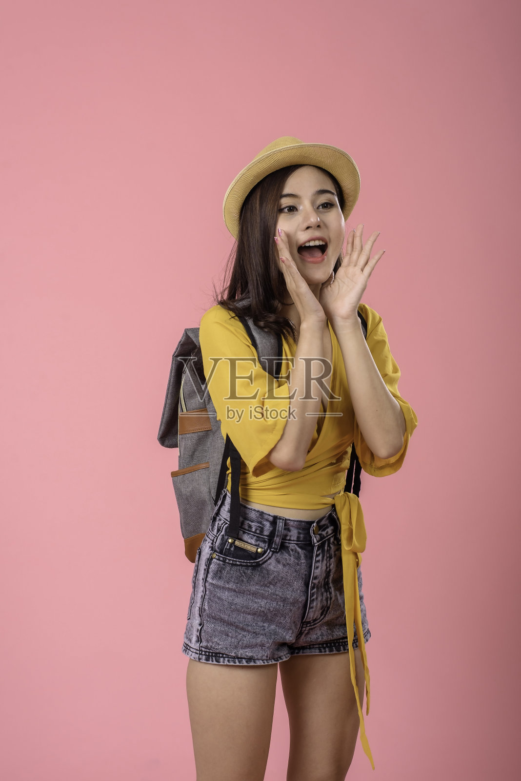 美丽的亚洲女性旅行者享受轻松的暑假,背着粉红色背景的小背包。照片摄影图片